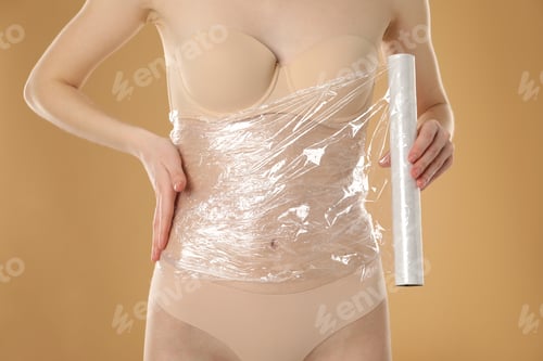 Preview: Woman doing spa body wraps on her belly against beige background, closeup