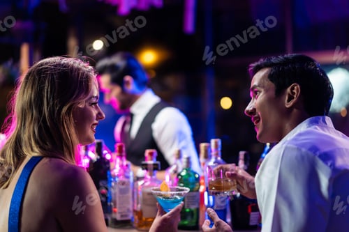 Preview: Beautiful young couple having fun, drinking alcohol cocktail in a bar.