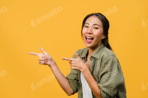 Preview: Portrait of young Asian lady smiling with cheerful expression on yellow background.