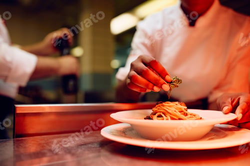 Preview: Close up of black professional cook serving a dish in a restaurant.