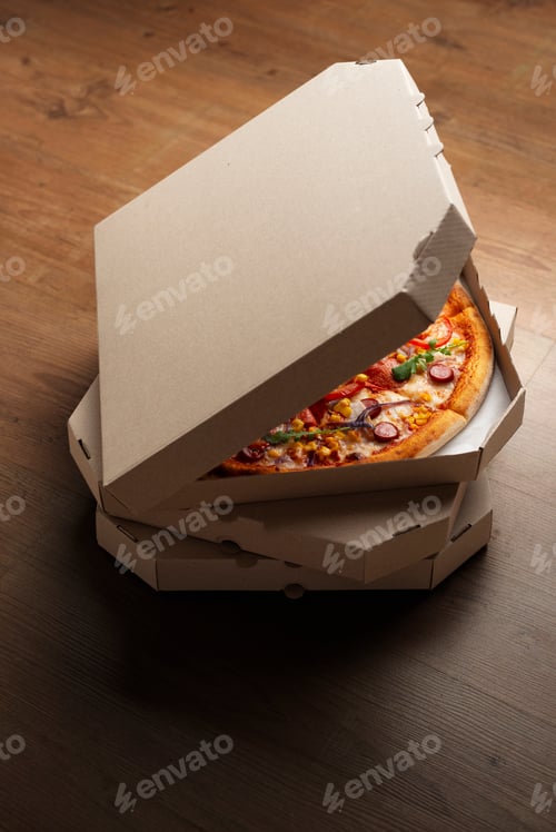 Preview: Pizza in open carton box on natural wooden table high angle view with copy-space