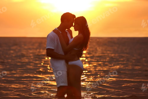 Preview: Happy young couple spending time together on sea beach at sunset