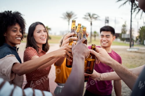 Preview: Close-up of hands of a group of young people of different races toasting happily at sunset. Cheers.