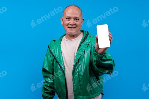 Preview: Smiling Mature Asian Man Holding Up Blank Smartphone Screen For Display Mockup