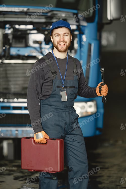 Preview: Young worker in uniform near truck with tools