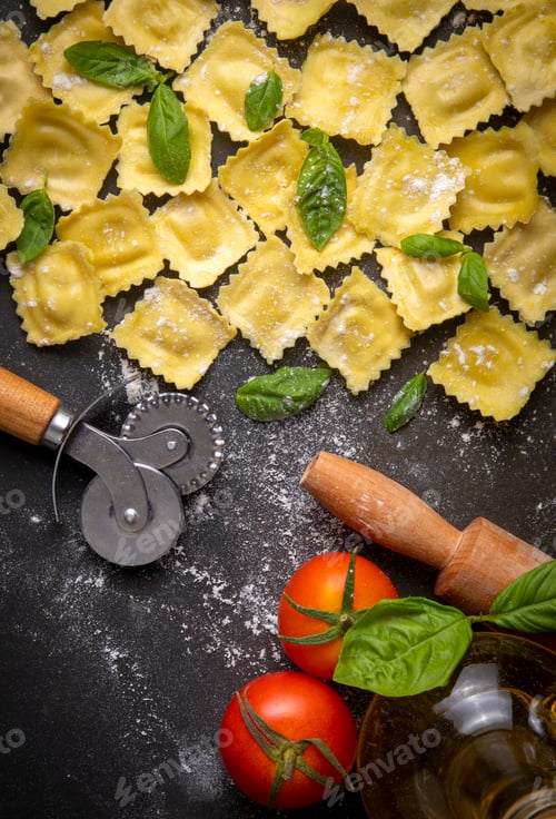 Preview: Delicious raw ravioli with flour and basil on dark background. The process of making Italian ravioli