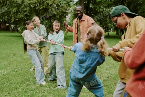 Preview: Multiethnic School Children and Male Teacher Playing Tug of War Outdoors