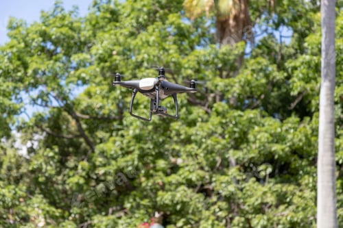 Preview: Closeup of a flying drone against green foliage of tr