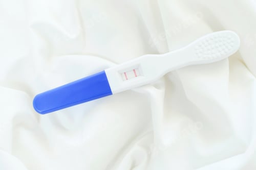 Preview: Positive pregnancy test with two stripes on white background, top view.