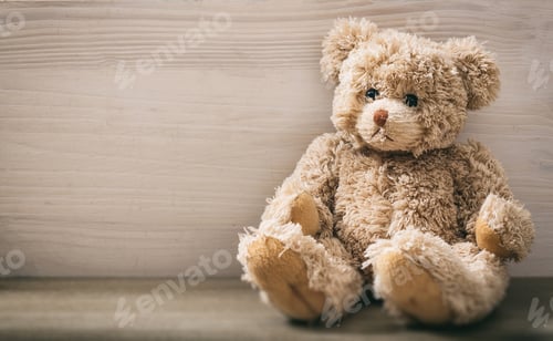 Preview: Teddy bear is sitting on an empty wooden background. Brown lonely sad fluffy animal toy. Copy space