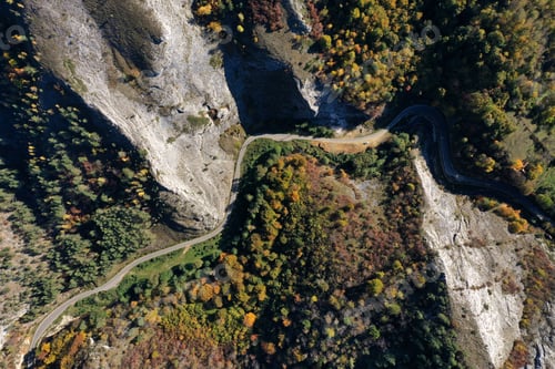 Preview: Aerial top down view of deep canyon, gorge road in autumn forest