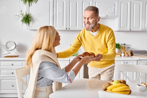Senior Couple Smiling, Sharing Breakfast in Bright Kitchen