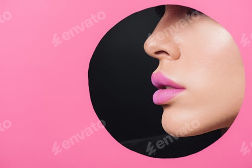 Preview: Cropped view of female face with pink lips in round hole in paper on black