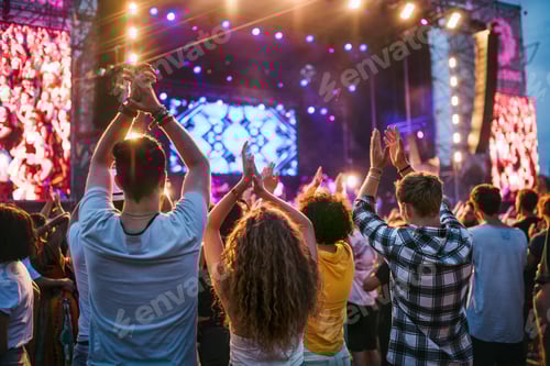 Preview: Rear view of group of young friends dancing at summer festival.