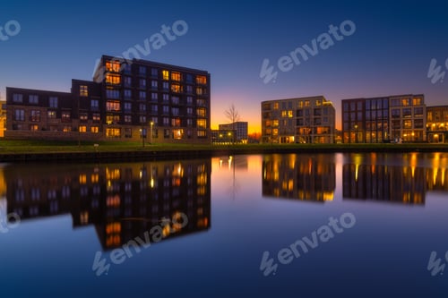 Preview: Amsterdam, Netherlands. A cityscape during sunset. A apartment building near the water in the bay.