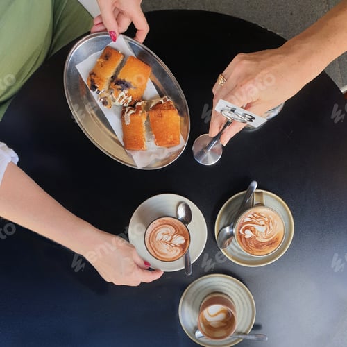 Preview: female hands holding coffee cup and food on table at cafe