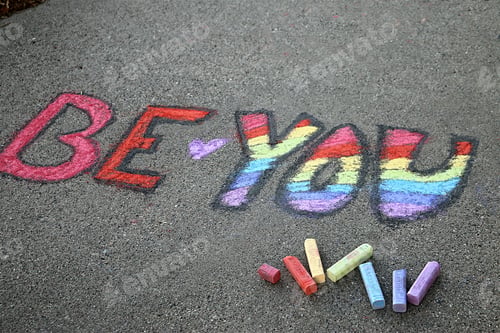 Preview: Be-You-nique: Be You written in rainbow colored chalk on the sidewalk in honor of pride celebration