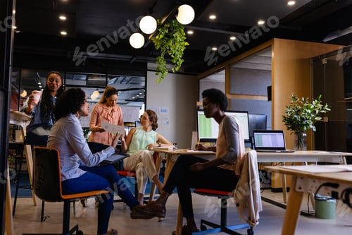 Preview: Diverse female colleagues in discussion using tablet in casual office meeting
