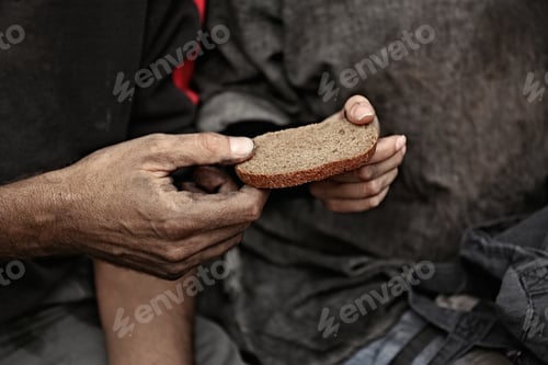 Preview: Poor homeless people sharing piece of bread outdoors, closeup