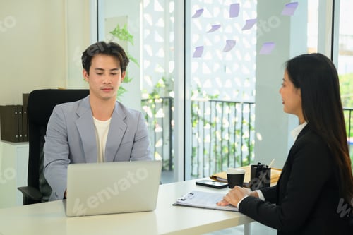 Preview: Asian male employe reviewing information on his laptop and evaluates candidate during an interview