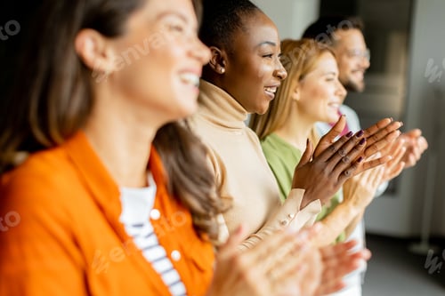 Preview: Young multiethnic startup team standing and applauding in the modern office