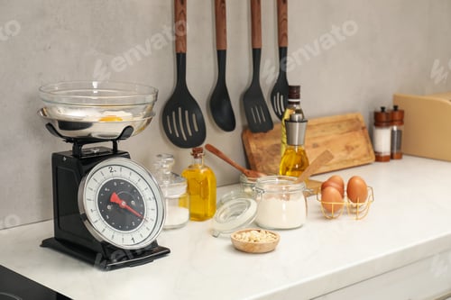 Preview: Retro mechanical kitchen scale and different food products on white marble countertop indoors