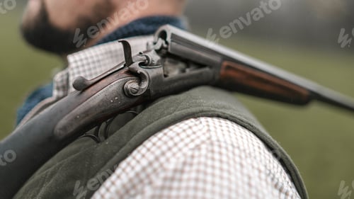 Preview: Close-up of unter man in traditional shooting clothes with shotgun on his shoulder.