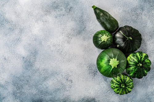 Vista previa: Green Summer squashes on washed concrete backdrop with copyspace, top view