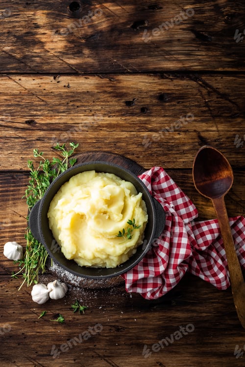 Vista previa: Puré de patatas, puré hervido en olla de hierro fundido sobre fondo rústico de madera oscura, vista desde arriba