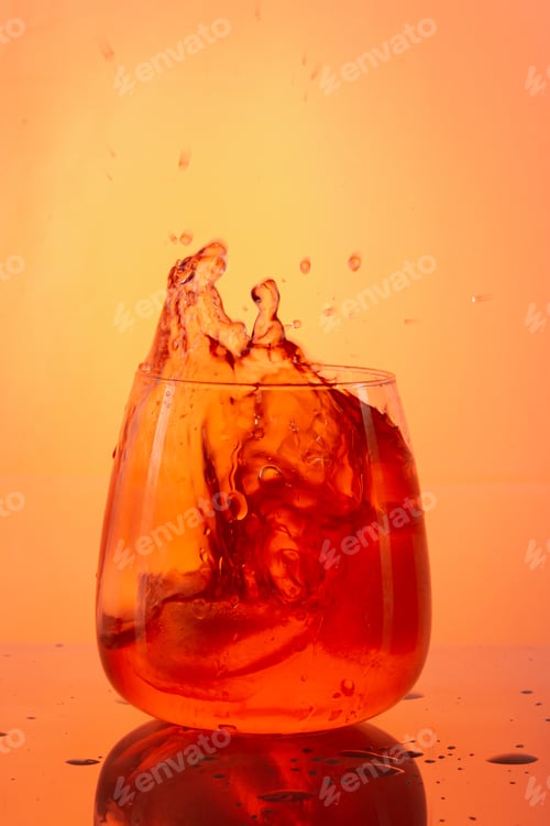Preview: Vertical shot of an orange cocktail splash on an orange background