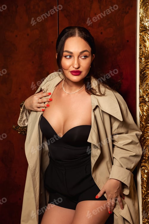 Preview: Fashionable cover woman in black dress and beige coat posing at brown wall