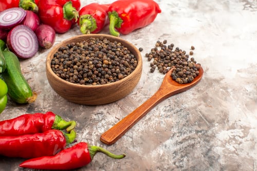 Preview: Side view of black pepper various chopped and whole vegetables on mixed color background