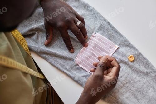 Preview: Above angle of hands of African American stylist sewing small patch on pants