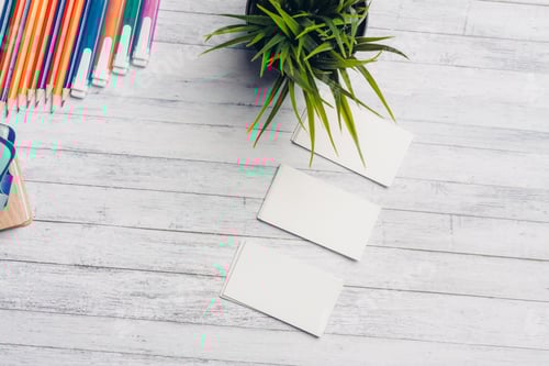 Preview: flower in a pot and white business cards on a wooden table office markers pencils paint
