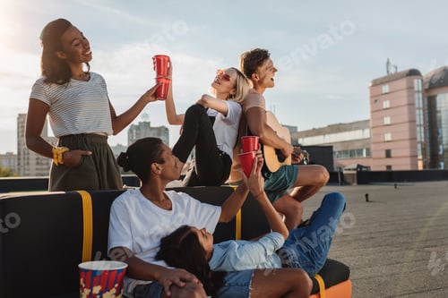 Preview: group of young happy friends having party and drinking alcohol on roof