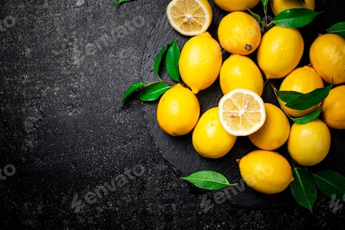 Preview: Juicy lemons with leaves on a stone board.