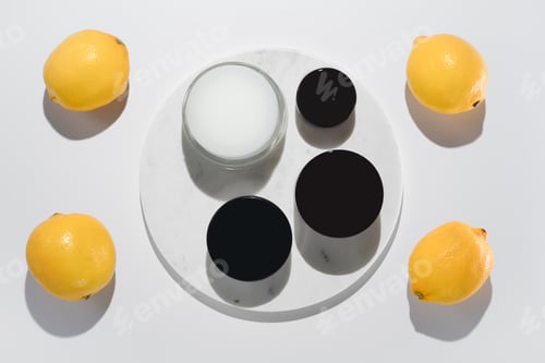 Preview: Fresh lemons and black and white round packaging next to marble circle background