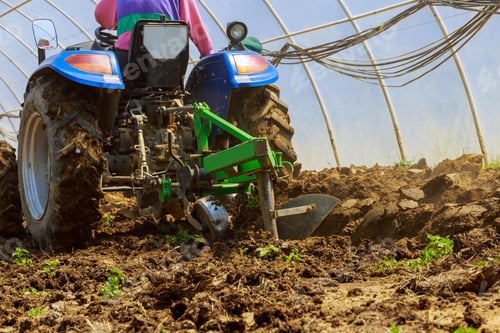 Preview: With aid of tractor, farmer plows greenhouse land, ensuring aconducive environment for crop growth.