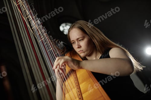 Preview: Portrait of Passionate Female Musician Playing Harp Performing Classical Music Indoors