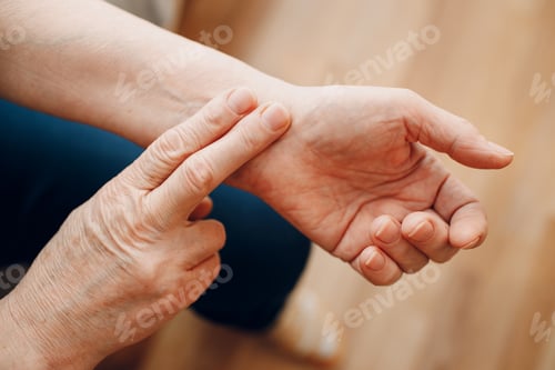 Preview: Female old hand measuring her own arm pulse. Elderly woman heart health