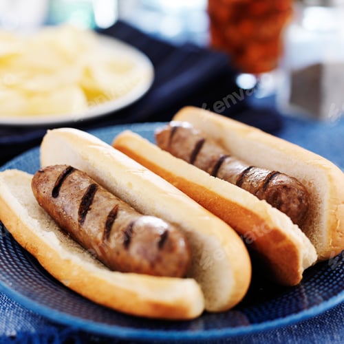 Preview: grilled bratwursts with potato chips and drink in the background