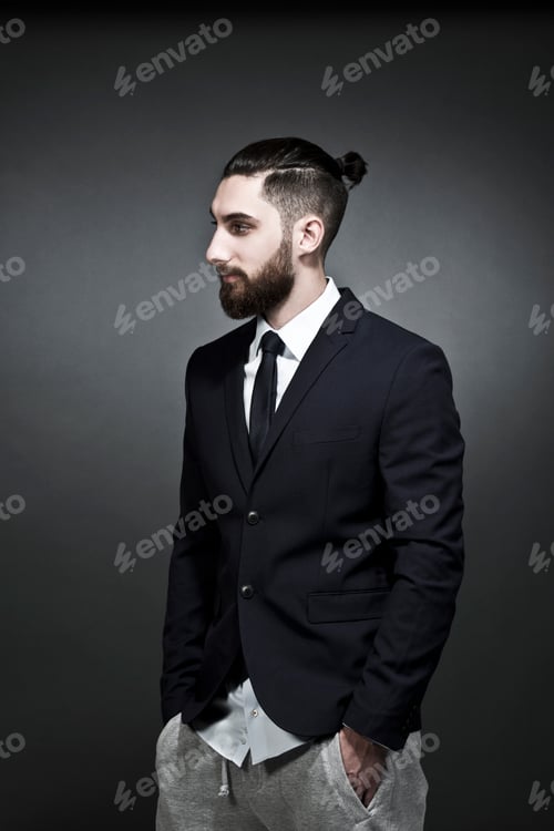 Preview: Portrait of young man wearing black jacket and jogging pants in front of grey background