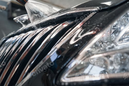 Preview: Car detailer washing black vehicle with pressured water