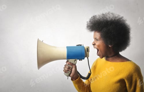 Preview: Beautiful young black woman looking yelling with a megaphone against a white wall