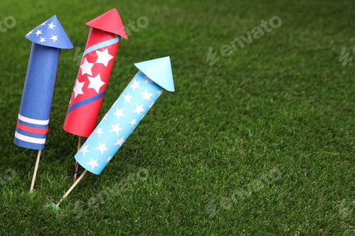 Preview: Firework rockets on green grass, closeup. Space for text