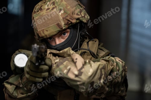 Preview: Young man in camouflage protective attire using lantern and gun