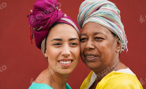 Preview: Portrait of african mother and daughter wearing traditional dress and turban with red background
