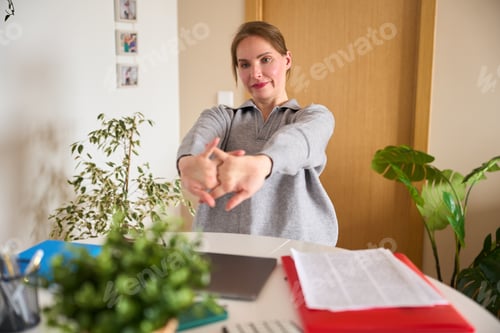 Preview: Woman stretching arms and hands at home office desk