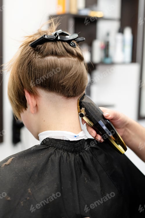 Preview: Teenager receiving a stylish haircut in a modern salon during the afternoon