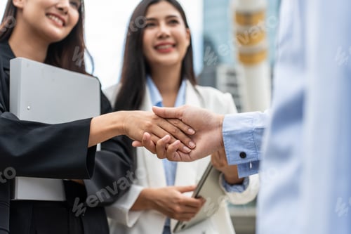 Preview: Close up of Asian businesswoman making handshake outdoor in the city.